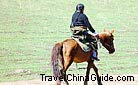 A local woman rides on horse on the Sangke Grassland. Oh, unknown heroine, turn back and let us see your face!
