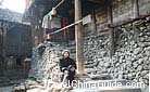 A granny sits on the stone steps before her house and enjoys the sunshine, Da Boji Miao Village